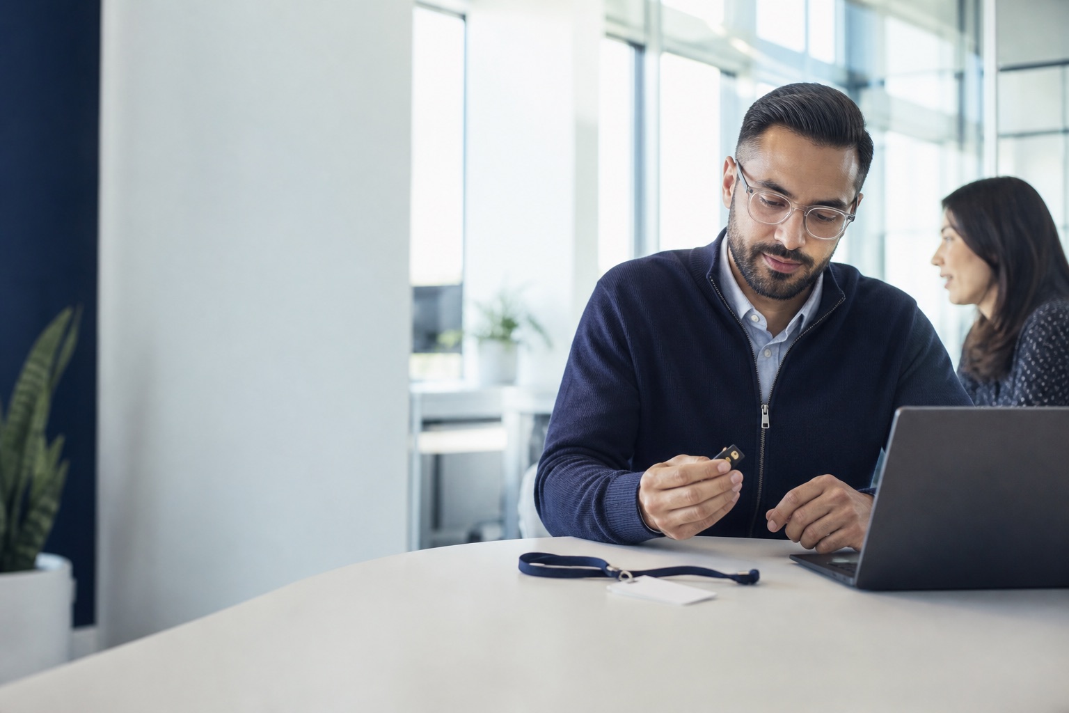IT administrator reviewing a hardware security key and an access credential in a bright office